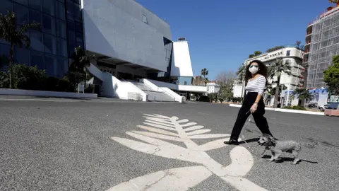 Una mujer con mascarilla pasea a su perro por la explanada que se extiende ante el Palais des Festivals de Cannes