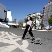 Una mujer con mascarilla pasea a su perro por la explanada que se extiende ante el Palais des Festivals de Cannes