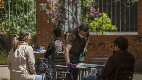El propietario del bar Arte y Sabor, desinfecta la mesa de un velador a la llegada de unos clientes El propietario del bar Arte y Sabor, desinfecta la mesa de un velador a la llegada de unos clientes