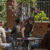 El propietario del bar Arte y Sabor, desinfecta la mesa de un velador a la llegada de unos clientes