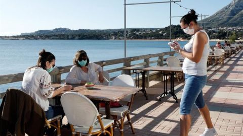 Personas en la terraza de un bar con mascarillas