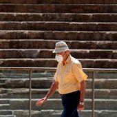 Una persona camina protegiéndose con una mascarilla. Una persona camina protegiéndose con una mascarilla.