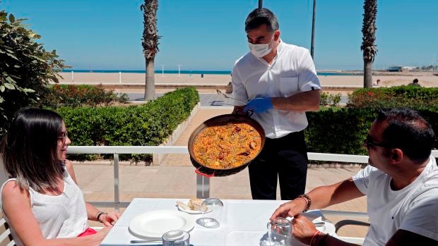 Un camarero sirve una paella en una terraza de un restaurante de la playa de la Malvarrosa de Valencia Un camarero sirve una paella en una terraza de un restaurante de la playa de la Malvarrosa de Valencia