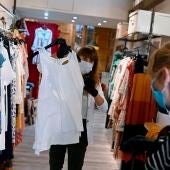 Una trabajadora muestra ropa a una clienta en un comercio de Alcalá de Henares, Madrid