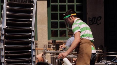 Un trabajador con pantalla protectora desinfecta una terraza en el primer d&iacute;a de la fase 1 en Ponferrada