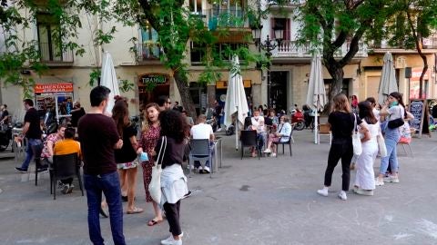 Varios j&oacute;venes hacen cola para sentarse en una de las terrazas de la plaza de la Vila del barrio de Gracia de Barcelona