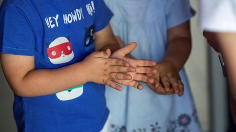 Dos ni&ntilde;os de desinfectan las manos con gel hidroalcoh&oacute;lico