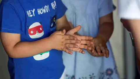 Dos niños de desinfectan las manos con gel hidroalcohólico Dos niños de desinfectan las manos con gel hidroalcohólico