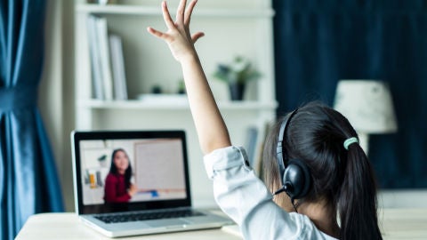 Ni&ntilde;a levanta la mano mientras atiende en una clase 'online'