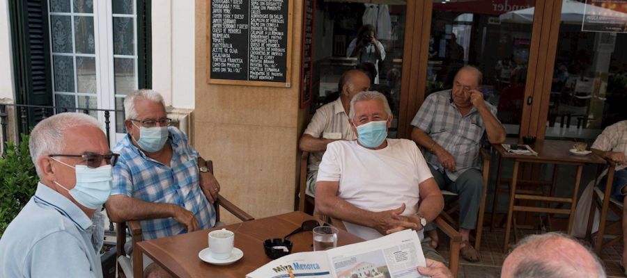 Un grupo de amigos tomando un café en un bar con la mascarilla puesta Un grupo de amigos tomando un café en un bar con la mascarilla puesta