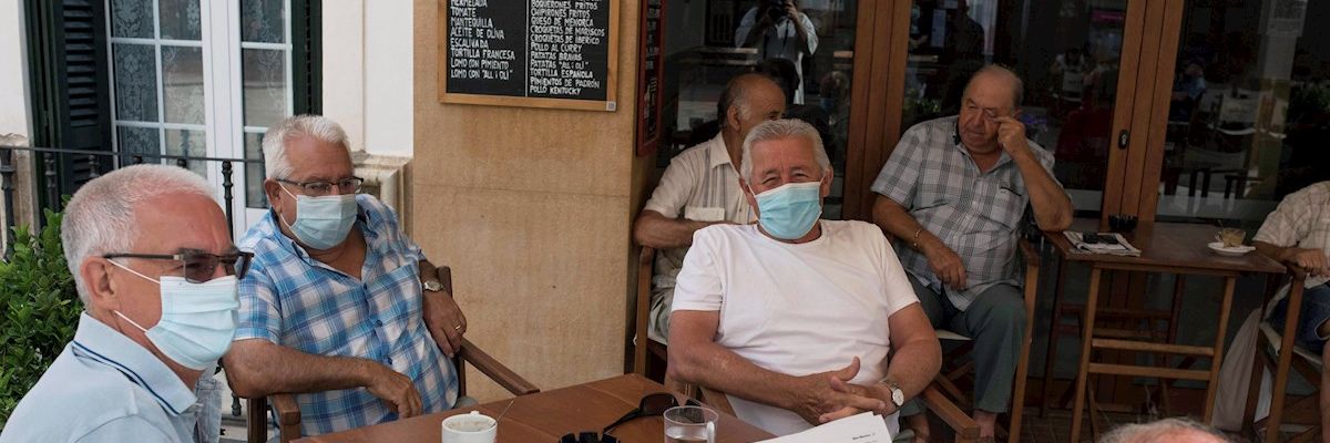 Un grupo de amigos tomando un café en un bar con la mascarilla puesta Un grupo de amigos tomando un café en un bar con la mascarilla puesta