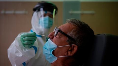 Una profesional sanitaria realiza una prueba PCR a un paciente en el CAP Raval Nord de Barcelona