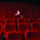 Un espectador espera el comienzo de la película en una sala de cine casi vacía
