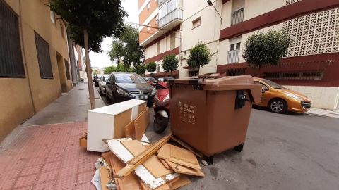 Enseres acumulados junto a un contenedor en Elda.