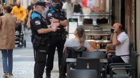 Dos agentes de la policía local de A Coruña se dirigen a un hombre que se encontraba fumando en una terraza de un bar Fumar en las terrazas