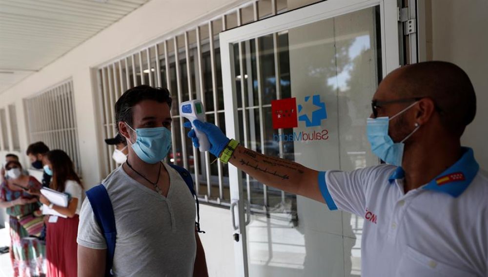 Un sanitario toma la temperatura a una de las personas que esperan su turno para realizarse una prueba de PCR dentro del Plan COVID-19 de la Comunidad de Madrid.