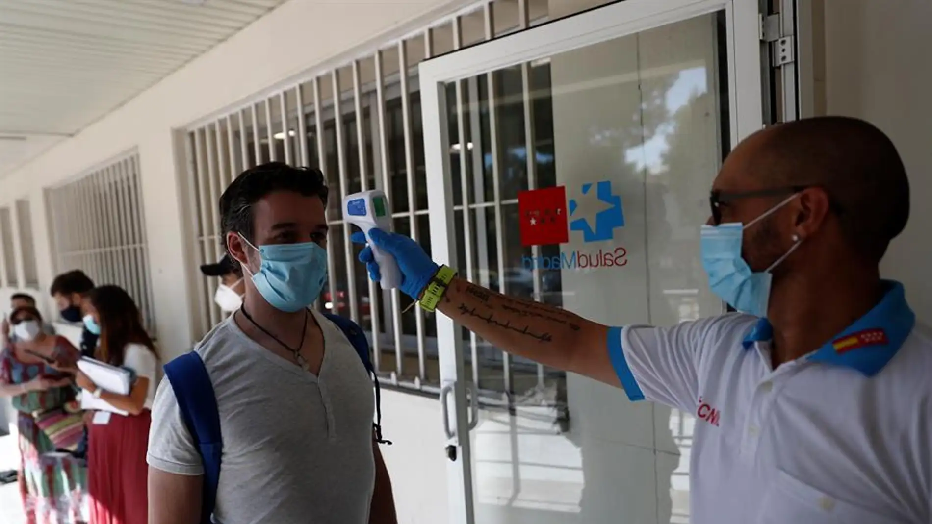 Un sanitario toma la temperatura a una de las personas que esperan su turno para realizarse una prueba de PCR dentro del Plan COVID-19 de la Comunidad de Madrid.