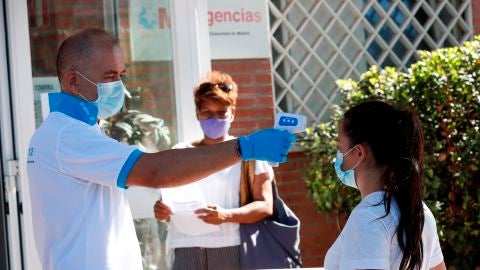 Un param&eacute;dico toma la temperatura a una ciudadana antes de acceder al centro de salud