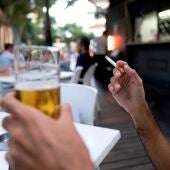 Una persona sostiene un cigarrillo en la terraza de en un bar