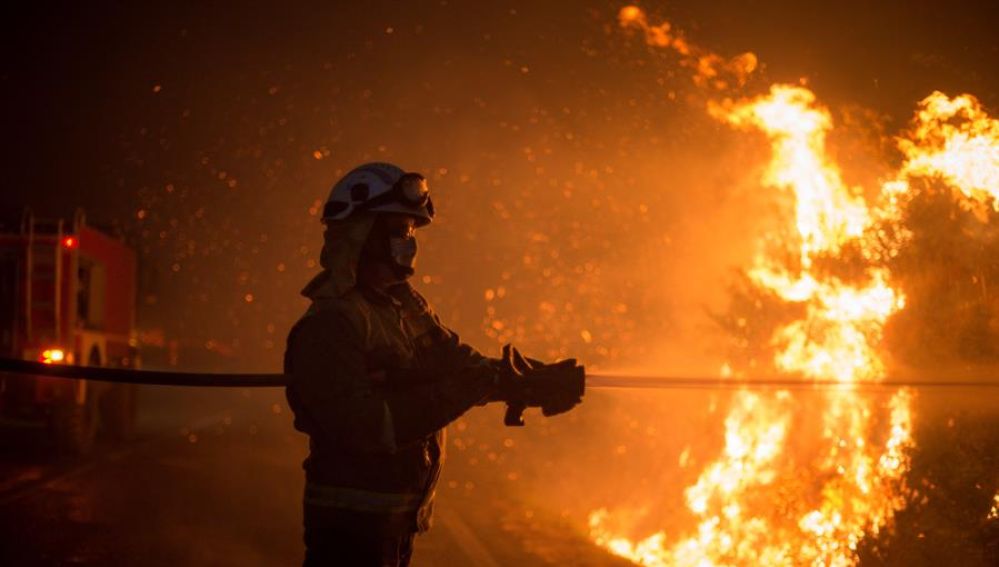  Varios bomberos realizan labores de extinción hoy domingo en el incendio forestal de Cualedro, Ourense