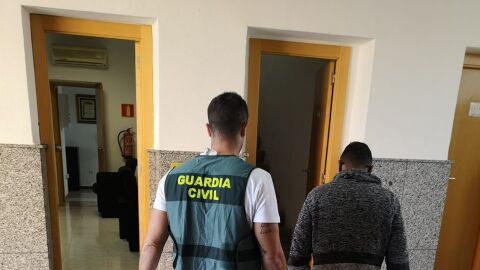 Un agente de la Guardia Civil con uno de los detenidos.