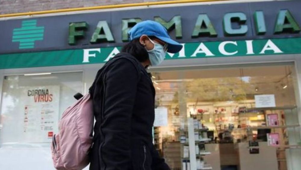 Una mujer pasa junto a una farmacia Una mujer pasa junto a una farmacia
