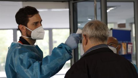 Personal sanitario del SERMAS toma la temperatura a una persona en la entrada del Centro de Mayores El Almendro (Madrid)