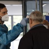 Personal sanitario del SERMAS toma la temperatura a una persona en la entrada del Centro de Mayores El Almendro (Madrid)