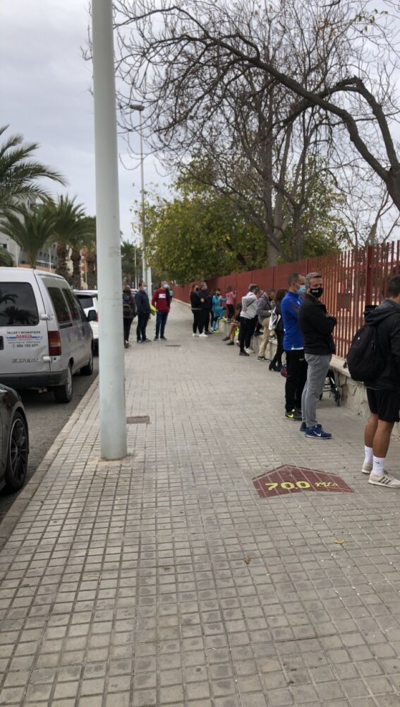 Personas junto al vallado de una instalación deportiva en Elche.