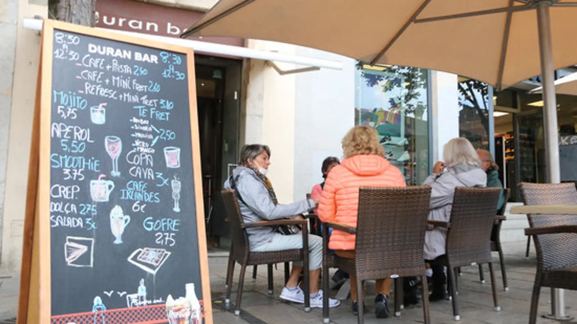 Un grup de persones consumient en un bar d'una terrassa de Girona
