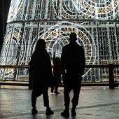 Una pareja y su hijo observan un árbol de navidad iluminado en la Plaza de la Marina, en Málaga. 
