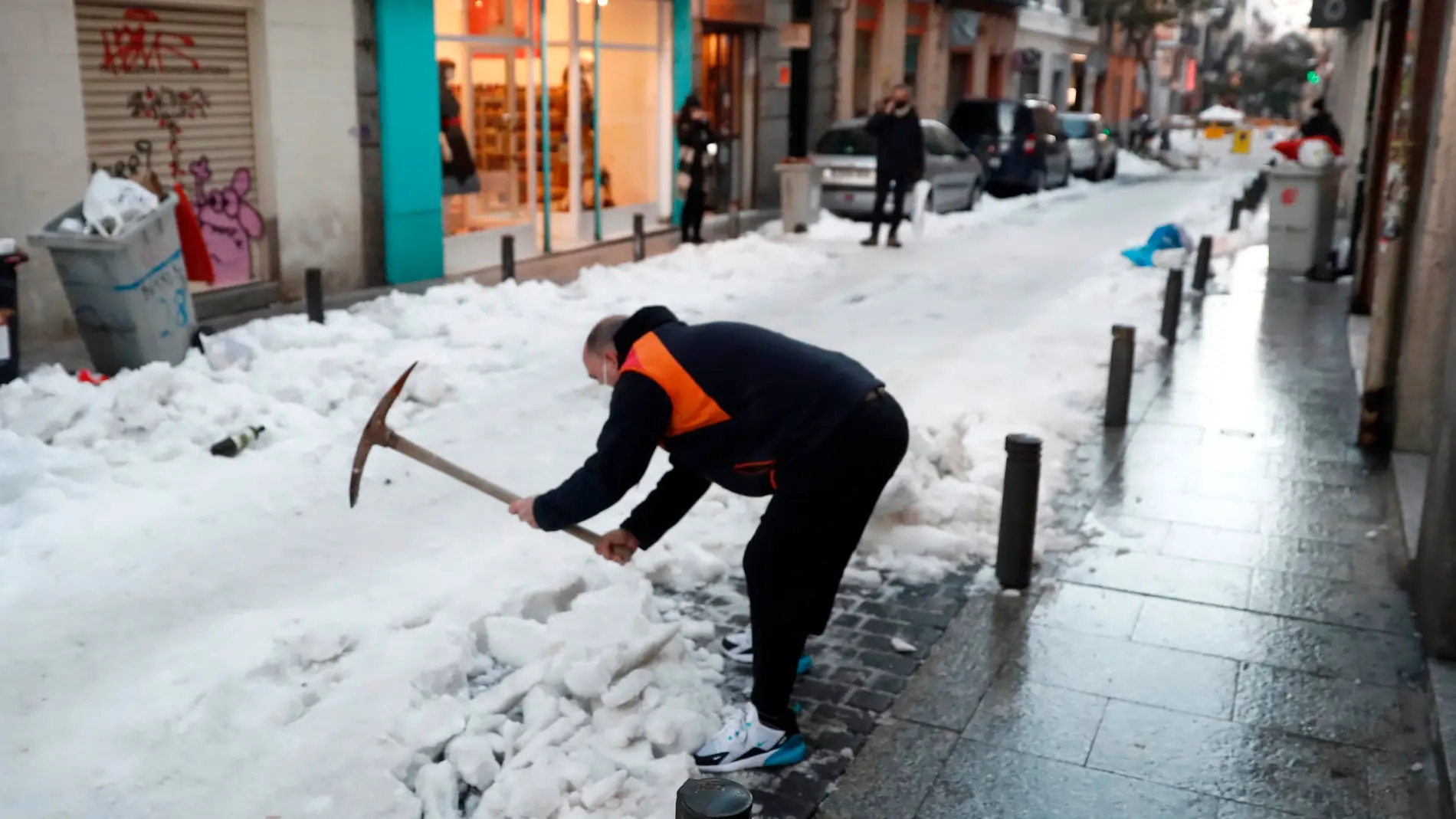 Un vecino retira nieve de la calzada en calle León de Madrid. 