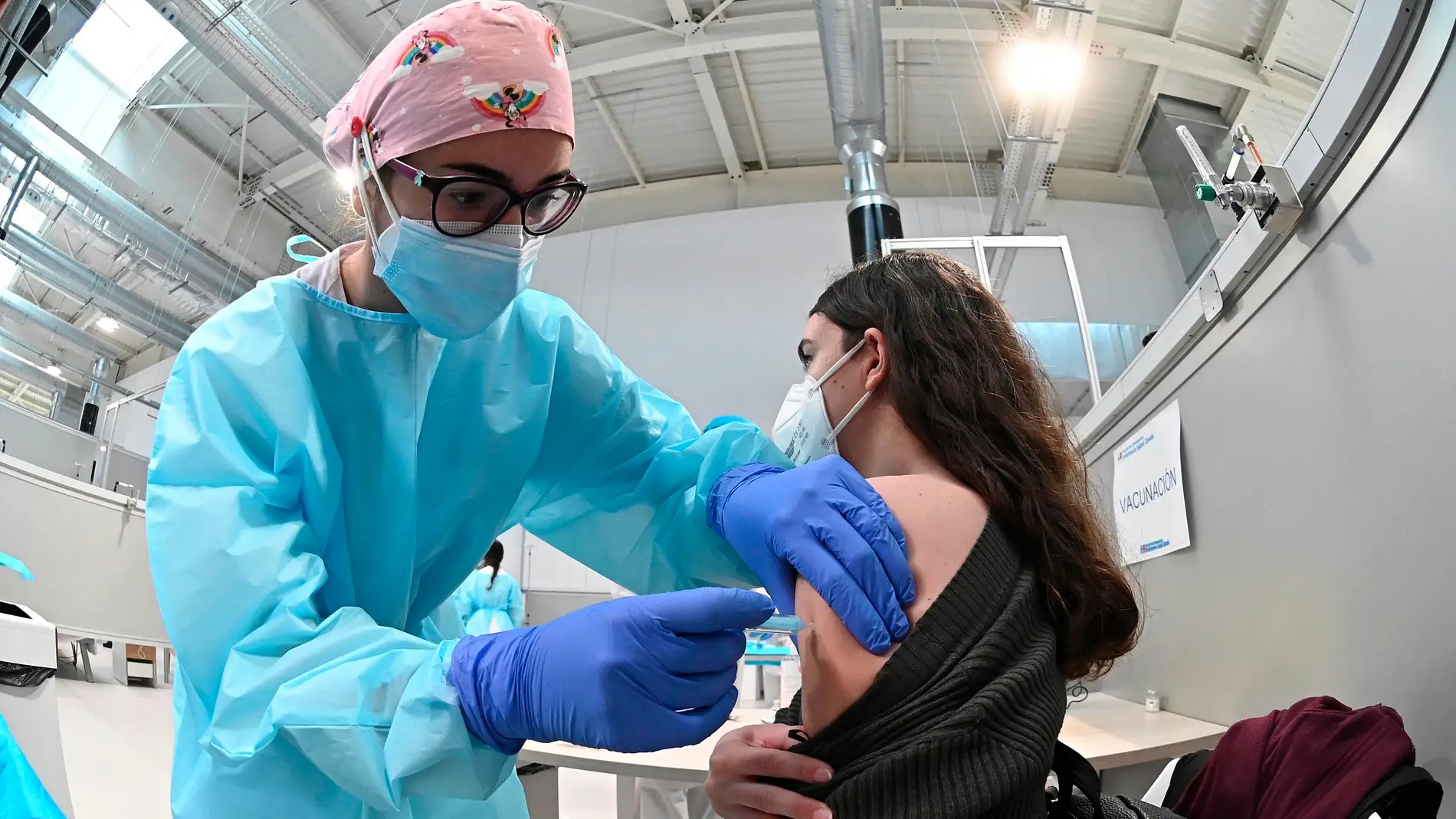 Una sanitaria pone la vacuna contra la covid-19 a una mujer en el hospital Isabel Zendal.