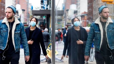 Personas con y sin mascarilla caminan por una calle de Nueva York