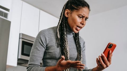 Mujer enfadada mirando el tel&eacute;fono