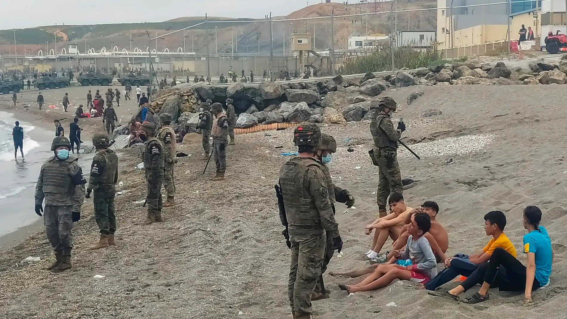 Miembros del Ejército observan a un grupo de inmigrantes que ha llegado a nado en los espigones fronterizos de Ceuta.