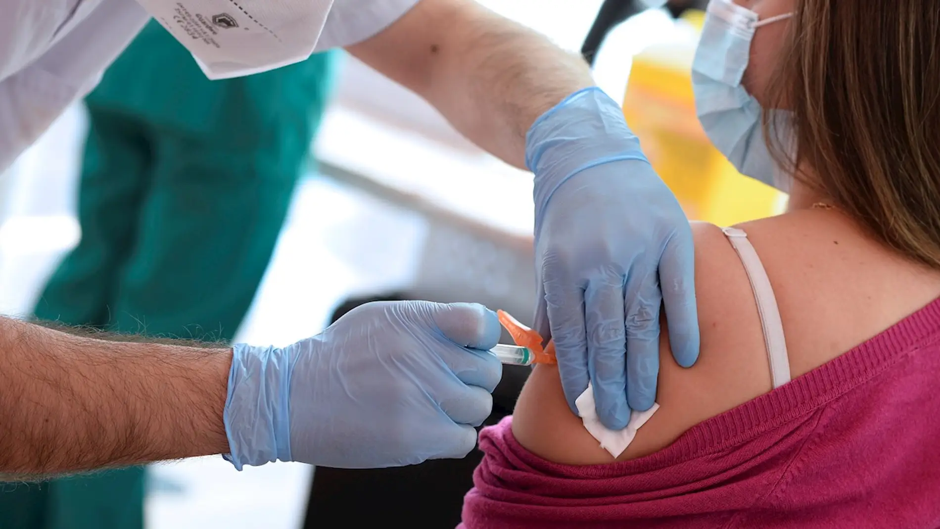 Un sanitario administrando a una ciudadana una vacuna contra el coronavirus.