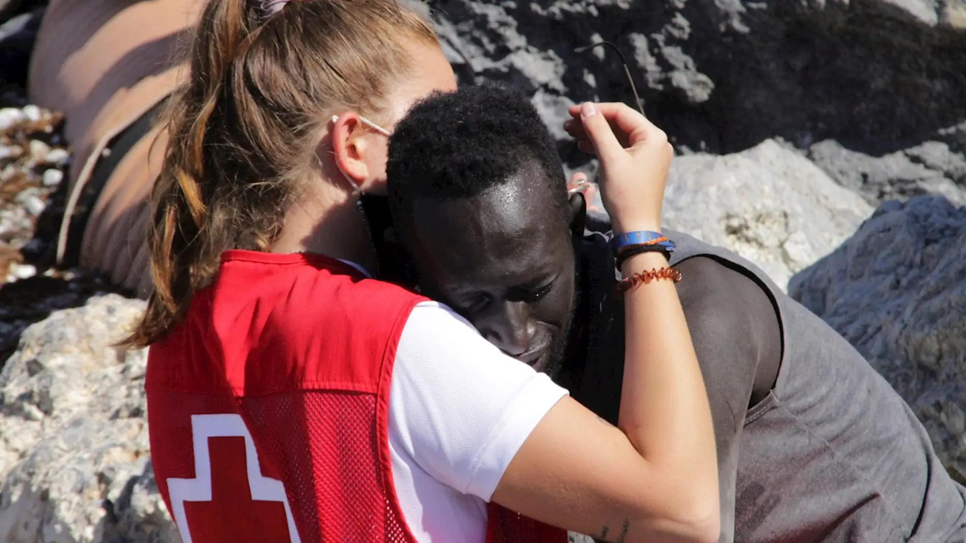 Una trabajadora de Cruz Roja abraza a un inmigrante que ha cruzado los espigones fronterizos