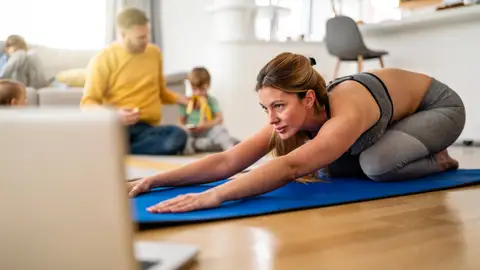 mujer haciendo ejercicio en casa con su familia detrás mujer haciendo ejercicio en casa con su familia detrás
