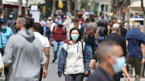 Personas con mascarilla caminan por la Gran Vía madrileña