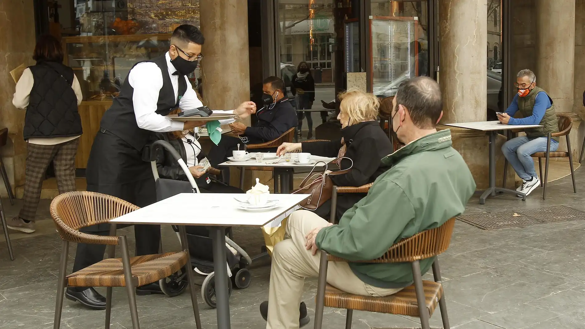 Un camarero atiende a varios clientes en la terraza de un bar en Palma.