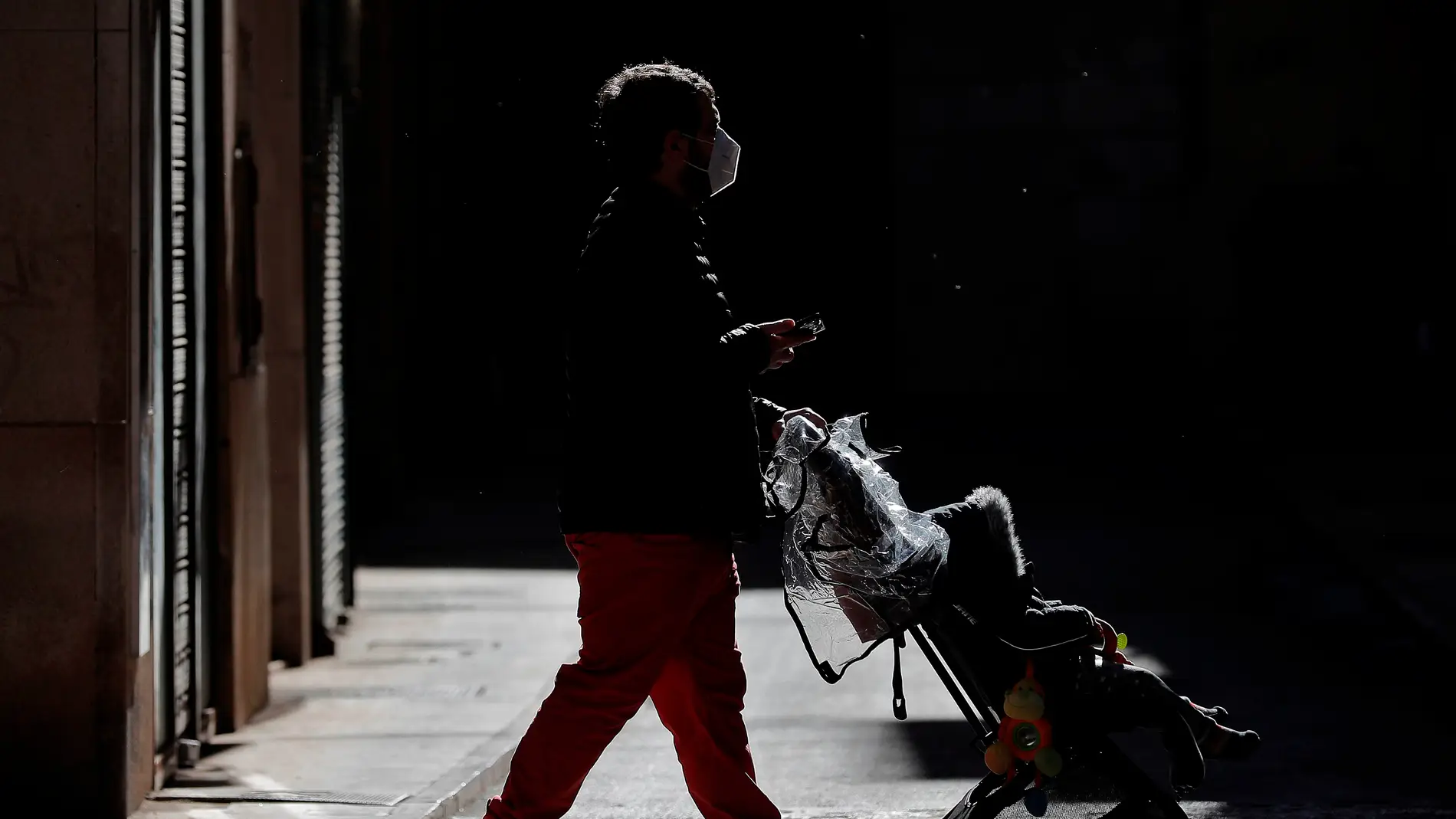 Un hombre pasea con un carrito de bebé por la ciudad de Valencia.