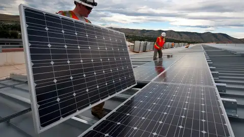 Un operari instal•la una placa solar Un operari instal•la una placa solar