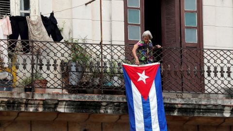 Una mujer sale al balc&oacute;n donde se expone una bandera cubana