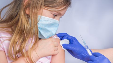 ni&ntilde;a con mascarilla a la que le ponen una vacuna