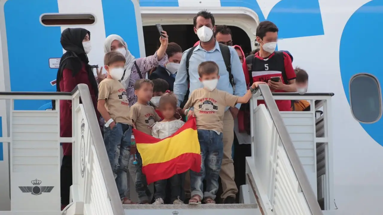 Una familia de evacuados afganos llega a la base de Torrejón con una bandera de España. Una familia de evacuados afganos llega a la base de Torrejón con una bandera de España.