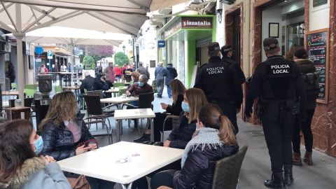 La policía local patrulla por una calle con veladores La policía local patrulla por una calle con veladores