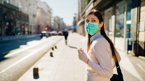 mujer con mascarilla en la calle mira hacia atrás con ansiedad