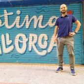 Javi Torrado, socio de Melicotó, posa frente a una barrera de Els Geranis (Palma) decorada con frases como "Avui fora nirvis" o "Bon dia tot lo dia"