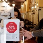 Personal de un hotel coloca un cartel a la entrada de su restaurante avisando de la obligatoriedad del pasaporte covid